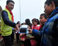 志愿者為貧困學生發放文具等新年禮物